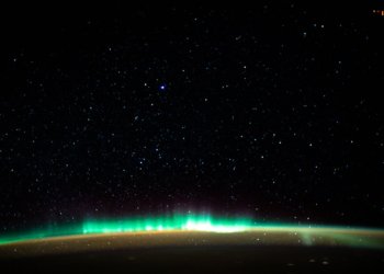 An aurora blankets the Earth beneath a celestial night sky